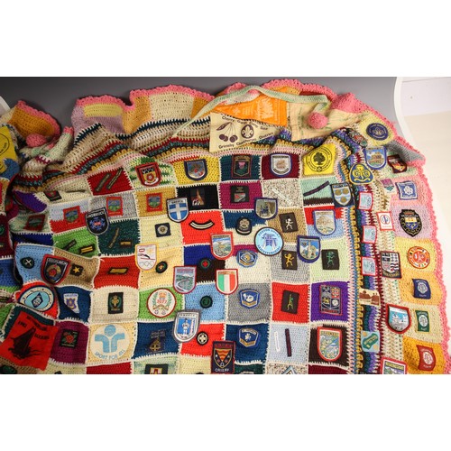 558 - SCOUTS/GUIDES INTEREST: A crocheted patchwork fireside blanket, late 20th century, extensively appli... 