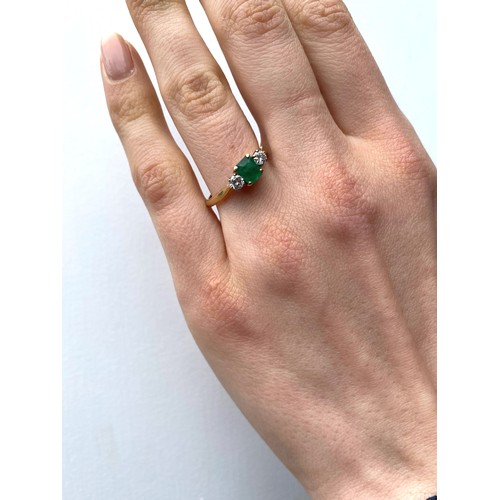 235 - A diamond and emerald 18ct gold three stone ring, the central rectangular cut emerald with round cut... 