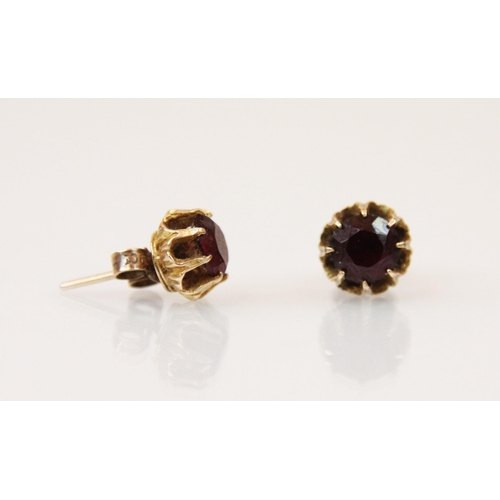 195 - A pair of red stone earrings, the round cut stone within a yellow metal claw setting with grooved de... 