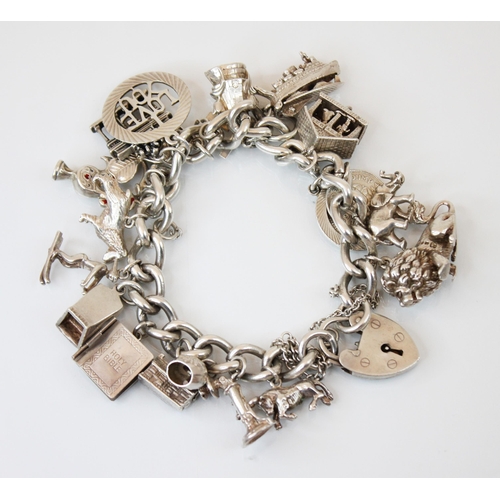 196 - A mid 20th century silver charm bracelet, the double curb link bracelet suspending twelve charms wit... 