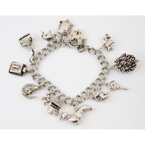 196 - A mid 20th century silver charm bracelet, the double curb link bracelet suspending twelve charms wit... 