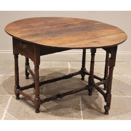 709 - A late 17th century oak gate leg table, the oval plank top above a single frieze drawer, upon ring t... 