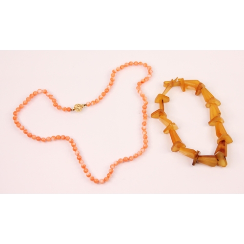 117 - A 'coral' bead necklace, the uniform round beads with an openwork yellow metal circular box and tong... 