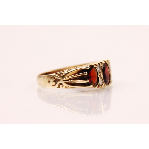 144 - A late 20th century garnet ring, the central oval cut garnet with smaller oval cut garnet to each si... 