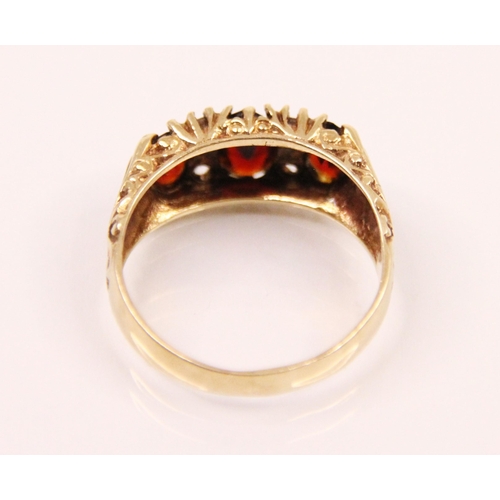 144 - A late 20th century garnet ring, the central oval cut garnet with smaller oval cut garnet to each si... 