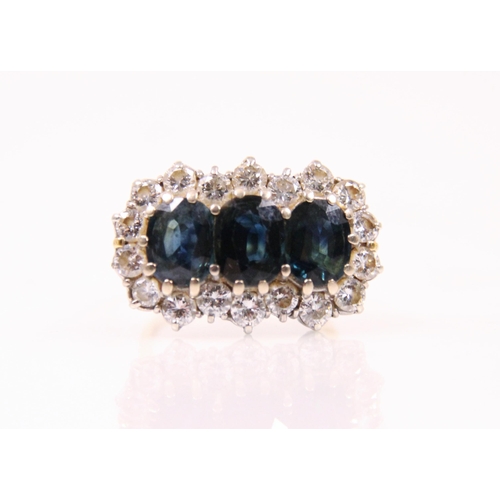 190 - A 20th century sapphire and diamond ring, the three oval cut sapphires within a surround of eighteen... 