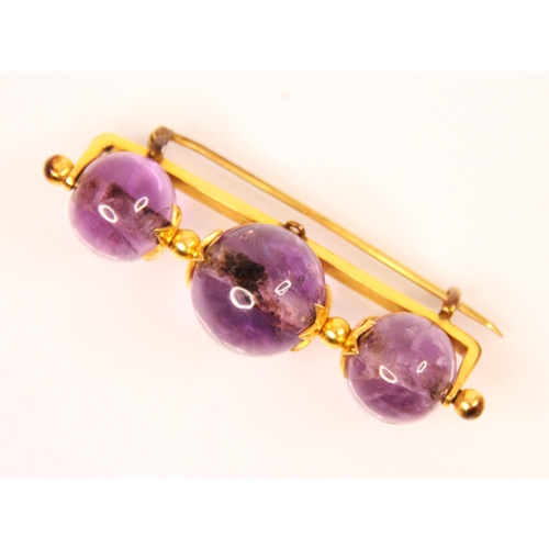 118 - An amethyst bar brooch, the central spherical amethyst with a graduated sphere to each side, with ye... 