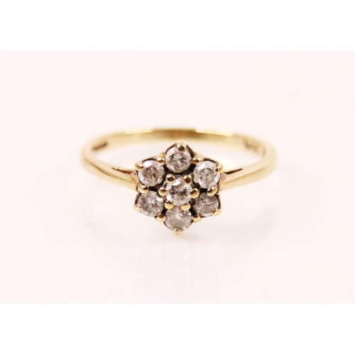 140 - A diamond cluster ring, the seven round cut diamonds designed as a flower head, within a yellow meta... 