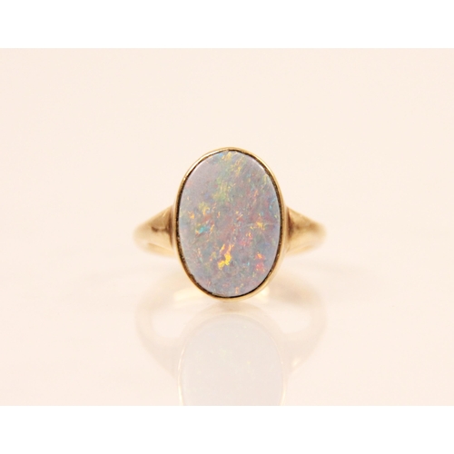 197 - An 'opal' ring, the oval shaped opal set within a rub over yellow metal mount and plain polished ban... 