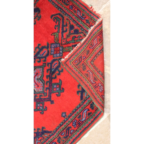 670 - A Turkish wool rug, in red, blue and green colourways, the three central openwork medallions, upon a... 