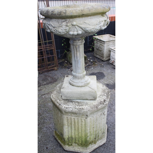 804 - A reconstituted stone garden urn, of bowl form, cast in relief with swags upon a fluted column, 70cm... 