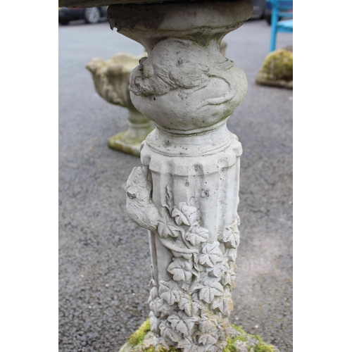 814 - A reconstituted stone bird bath, the shallow circular well upon a fluted pedestal, cast in relief wi... 