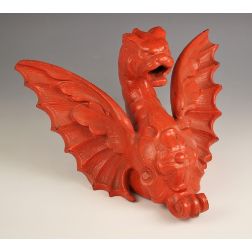 612 - A cast iron red painted decorative bracket modelled as a winged dragon, 30cm wide