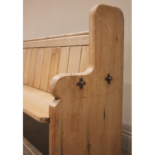 742A - A Victorian pine pew, the shaped end supports united by a board seat, panelled back and rear book sh... 