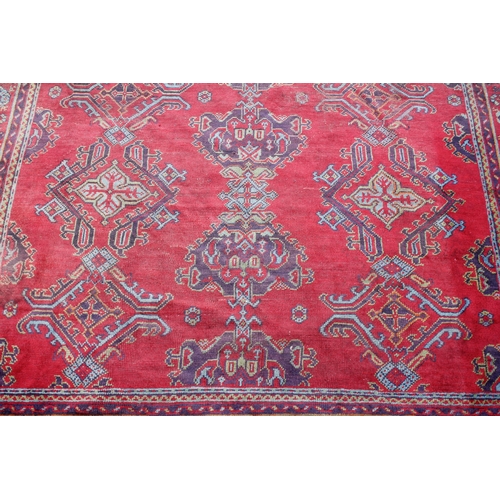 667 - A Turkish wool carpet, in vibrant red, blue and green colourways, the central field with multiple ge... 