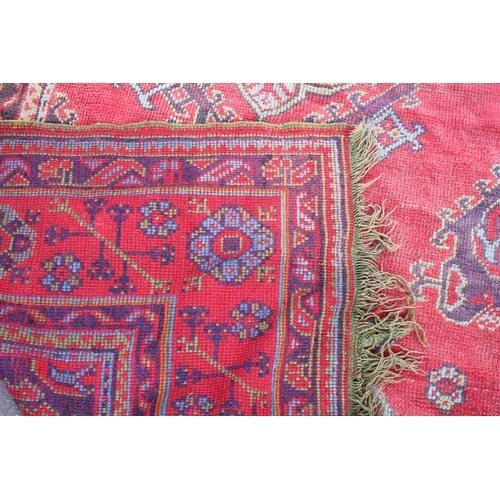 667 - A Turkish wool carpet, in vibrant red, blue and green colourways, the central field with multiple ge... 