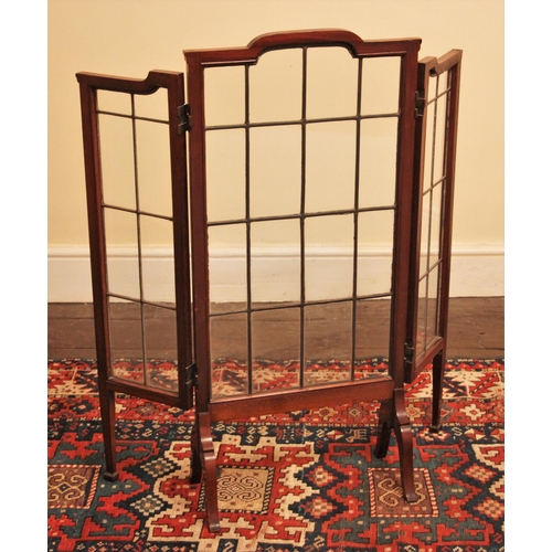 674 - * An Edwardian mahogany framed leaded glass folding fire screen, the central break arch panel upon d... 