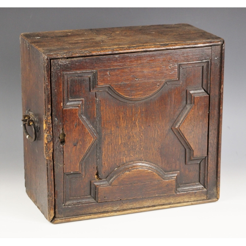 693 - A 17th century oak spice cupboard, with iron swing handles to the sides, the geometrically moulded d... 