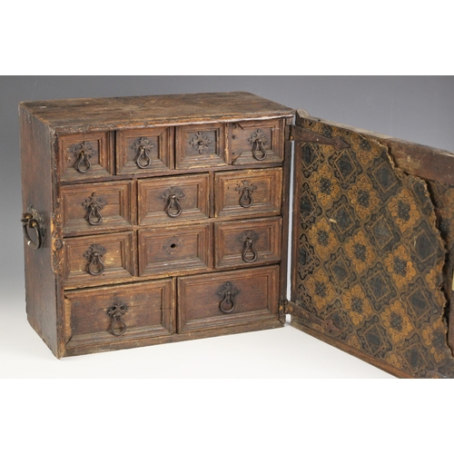 693 - A 17th century oak spice cupboard, with iron swing handles to the sides, the geometrically moulded d... 