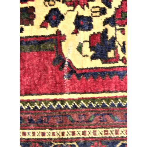 1052 - A Persian pattern wool carpet, in red, blue and ivory colourways, the central angular medallion with... 