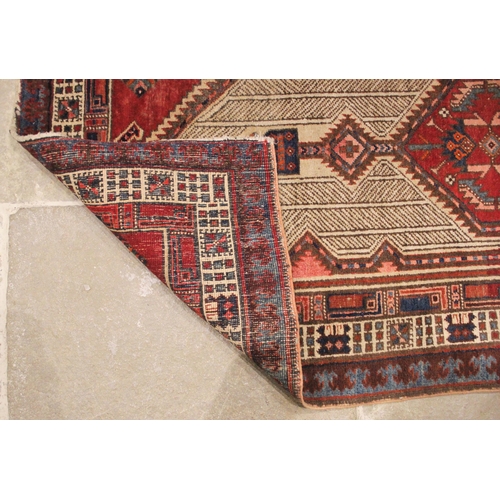 1056 - A Baluchistan wool rug, in red, blue and ivory colourways, the elongated central medallion, enclosed... 