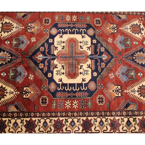 1060 - A Caucasian design wool rug, in oxidized red, blue, ivory and green colourways, the central geometri... 