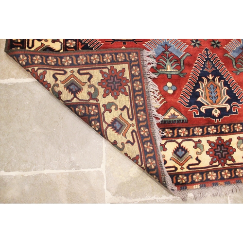 1060 - A Caucasian design wool rug, in oxidized red, blue, ivory and green colourways, the central geometri... 