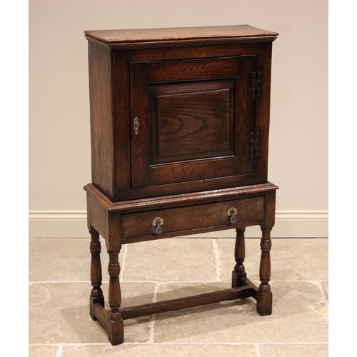 1089 - A mid 18th century oak spice cupboard on stand, the moulded cornice over a single fielded panelled d... 