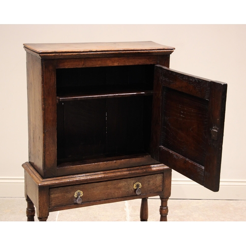 1089 - A mid 18th century oak spice cupboard on stand, the moulded cornice over a single fielded panelled d... 