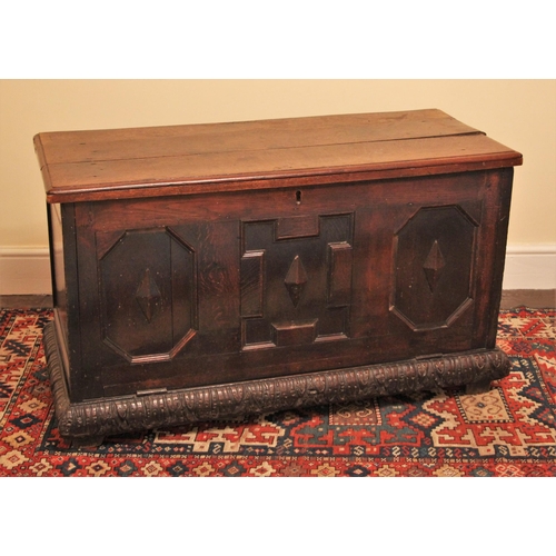 1091 - A 17th century oak coffer, the hinged plank top opening to a later central division, over three geom... 