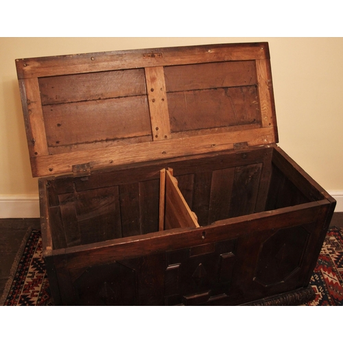 1091 - A 17th century oak coffer, the hinged plank top opening to a later central division, over three geom... 