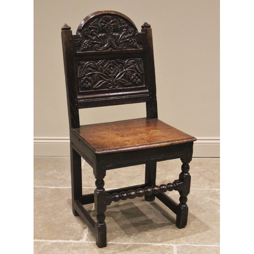 1094 - A joined oak back stool, late 17th/early 18th century, the break arch back rest carved with fruit an... 