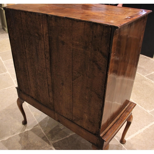 1097 - A George II walnut chest on stand, mid 18th century, the quarter veneered and crossbanded top over a... 