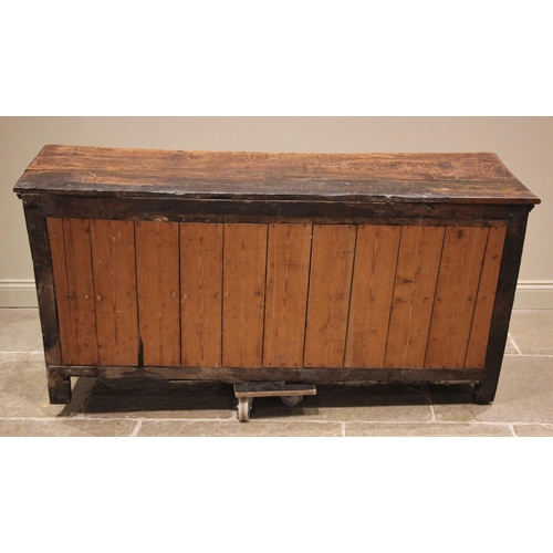 1100 - An early 18th century elm dresser base, the figured and moulded, oversailing top above an arrangemen... 