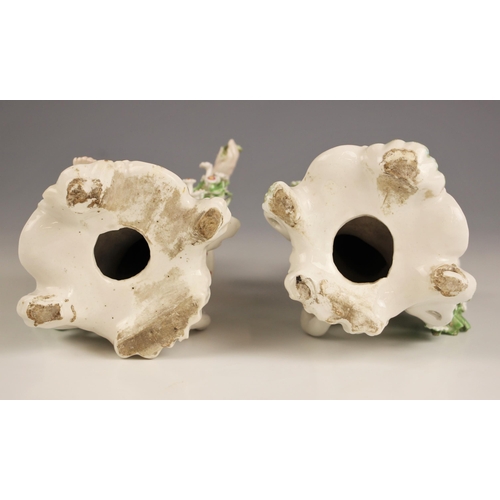 806 - A pair of German porcelain chamber sticks, early 19th century, modelled as putti perched upon bocage... 