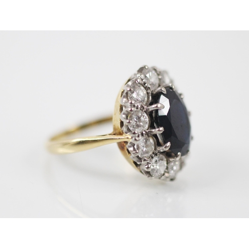 178 - An Edwardian style sapphire and diamond cluster ring, the central oval cut sapphire claw set in whit... 