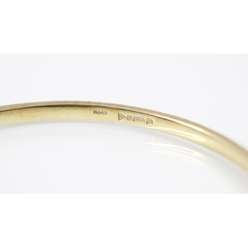 193 - An early 20th century 9ct yellow gold bangle, the bangle with engraved engine turned detail  through... 