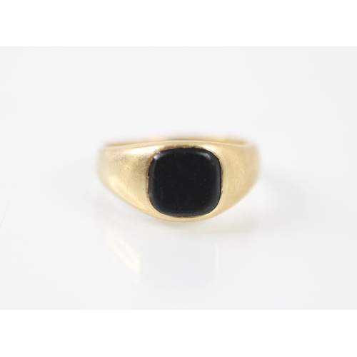 241 - A yellow metal and onyx set signet ring, the square onyx matrix set within wide shoulders and plain ... 