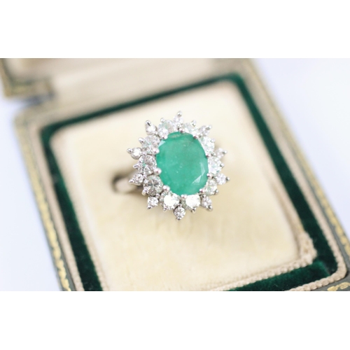 273 - An emerald and diamond cluster ring, the central emerald, claw set within a surround of twenty brill... 