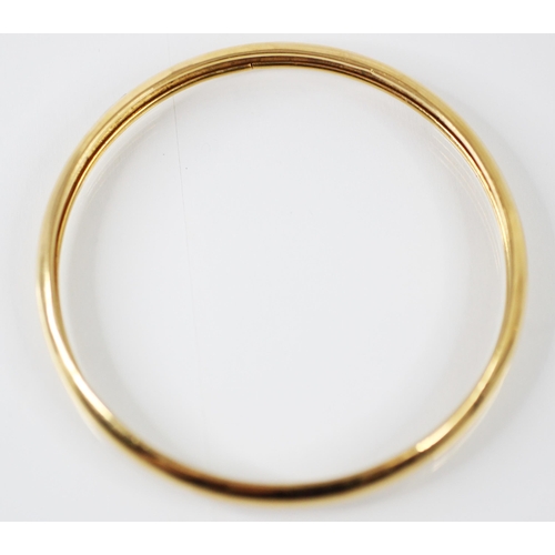 209 - A yellow metal bangle, the plain polished bangle with grooved interior, stamped 'K21' inner diameter... 