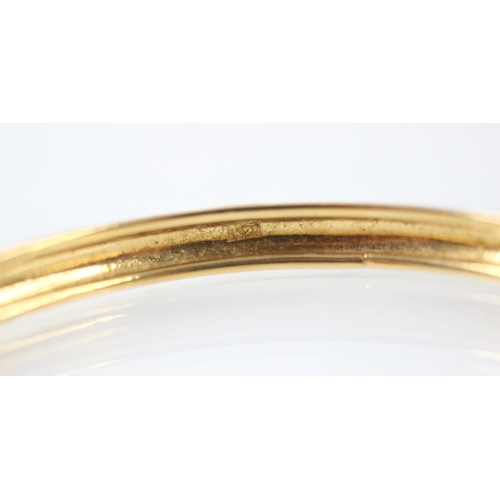 209 - A yellow metal bangle, the plain polished bangle with grooved interior, stamped 'K21' inner diameter... 