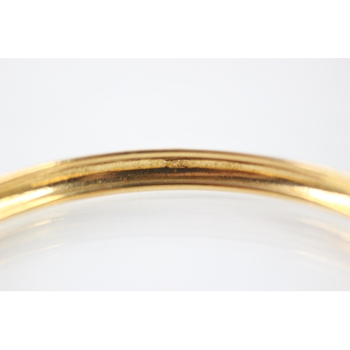 210 - A yellow metal bangle, the plain polished bangle with grooved interior, stamped 'K21' inner diameter... 