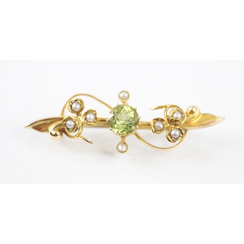 293 - An Edwardian seed pearl and untested peridot brooch, the central round cut peridot within a sinuous ... 