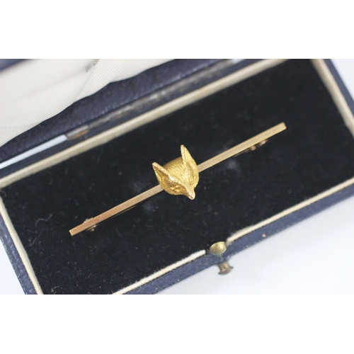 294 - A yellow metal fox head bar brooch, the plain polished bar with realistically chased fox head mask t... 