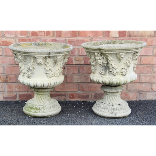 1235 - A pair of reconstituted stone garden urns, of campana form, moulded in relief with leaf and berry sw... 