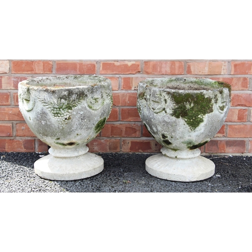 1236 - A pair of reconstituted stone garden urns, of cup form, moulded in relief with rings united by leaf ... 