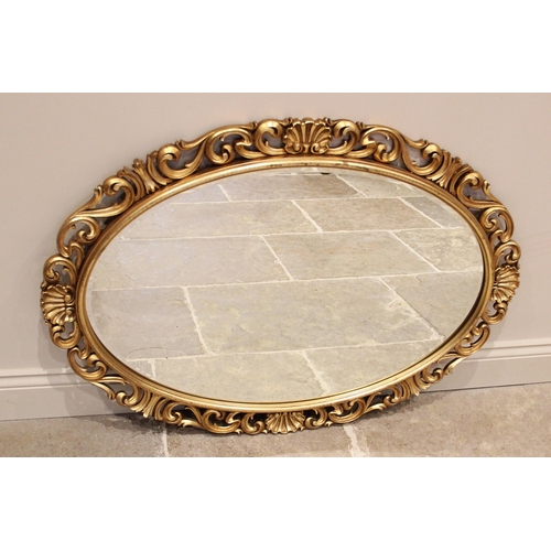 1066 - A gilt composite Florentine oval wall mirror, late 20th century, the scrolling openwork frame punctu... 