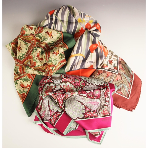 1028 - Four Liberty of London silk scarves, to include; a peacock and vase pattern narrow scarf in fuchsia,... 