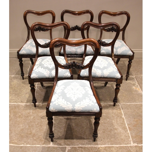 1064 - A set of six Victorian rosewood compressed balloon back dining chairs, each with a carved leafy cres... 