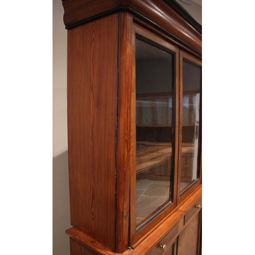 1087 - A pitch pine glazed bookcase, late 19th century, the ogee moulded cornice embellished with ebonised ... 